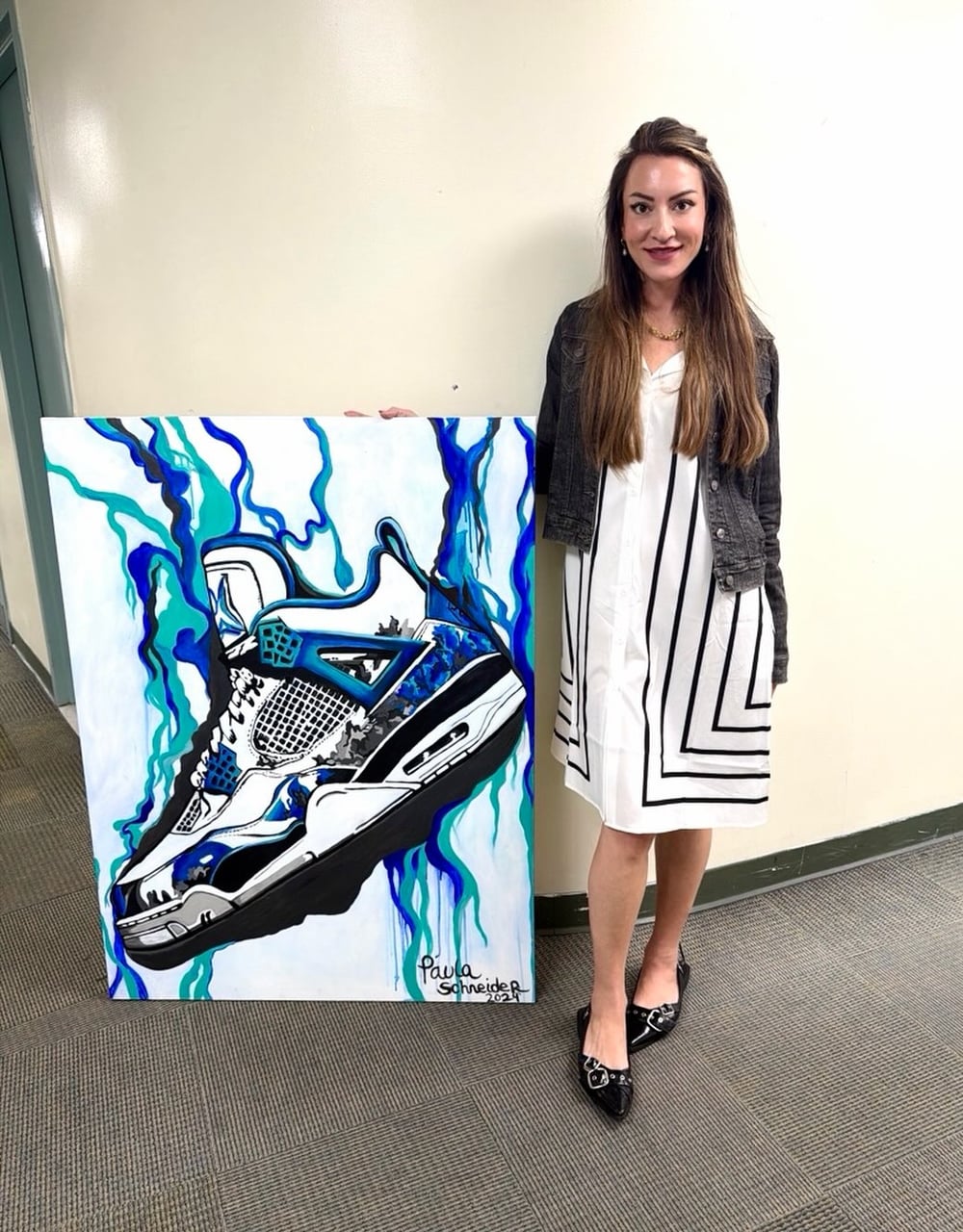 Paula standing beside her finished sneaker canvas, signed Paula Schneider