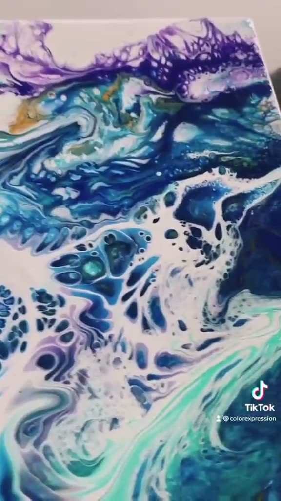 Blue and white acrylic paint lacing across a canvas