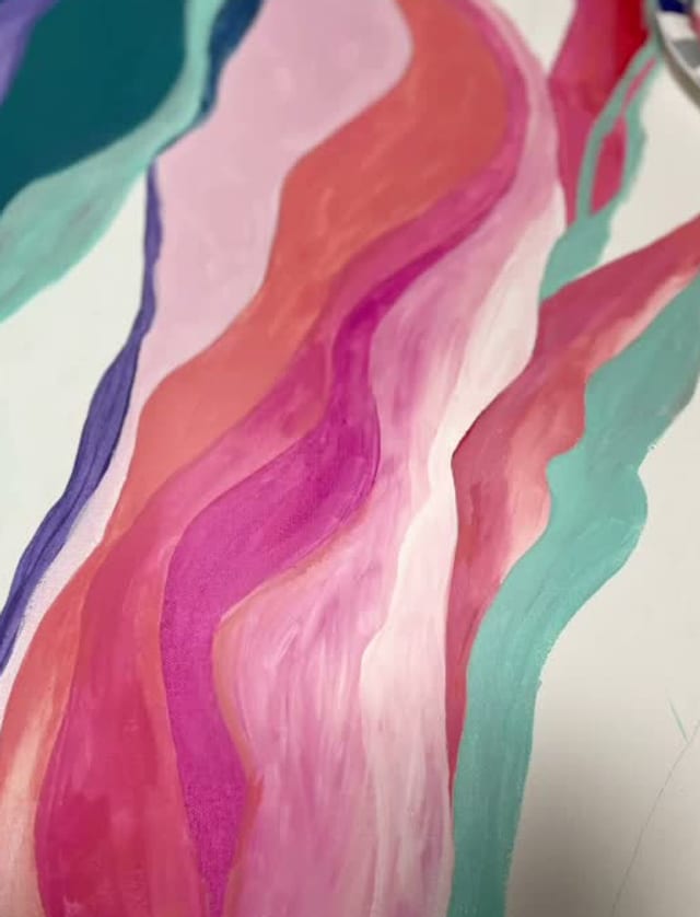 Pink and teal waves painted across a canvas